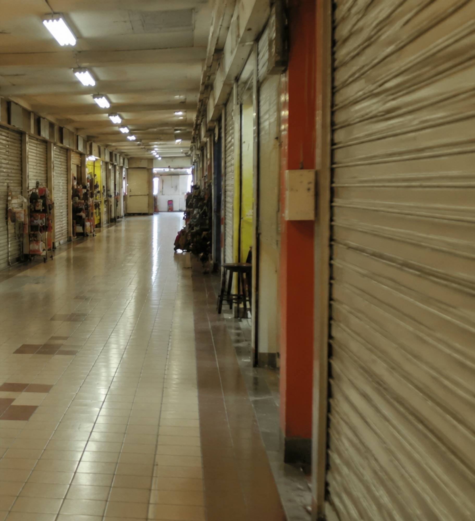 Grey roller shutters pulled down along a quiet mall corridor